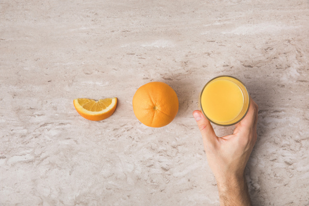 rajattu kuva mies ottaa lasi tuoretta appelsiinimehua pöydästä
 - Valokuva, kuva