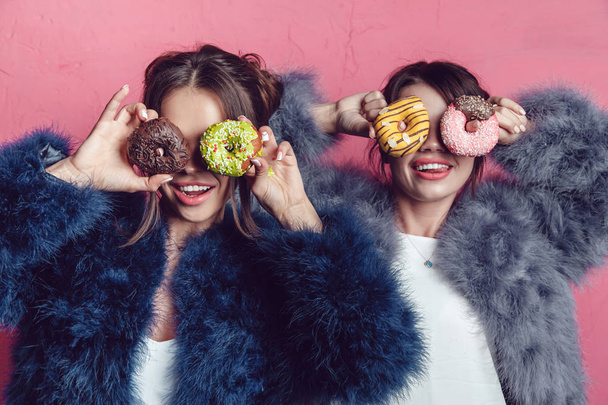 Beautiful girls with donuts posing on pink background. - Foto, Imagen