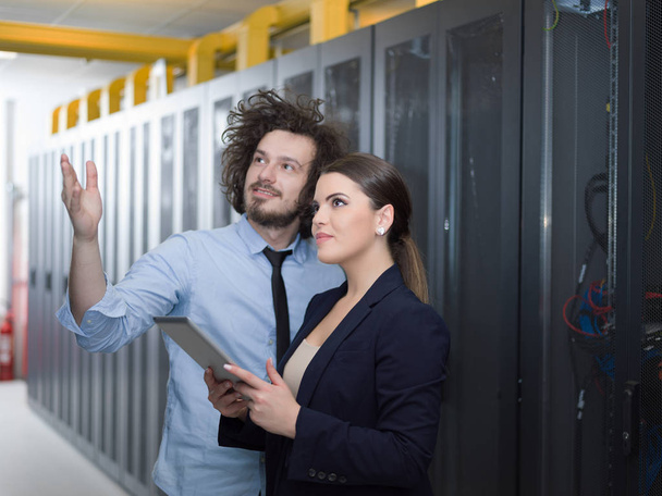 engineer showing working data center server room to female chief - Foto, afbeelding