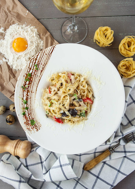 İtalyan tagliatelle makarna un ve yumurta sarısı gri bir ahşap masa üzerinde tavuk ve sebze ile - Fotoğraf, Görsel