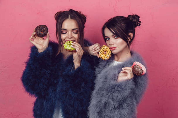 Beautiful girls with donuts posing on pink background. - Foto, Imagen