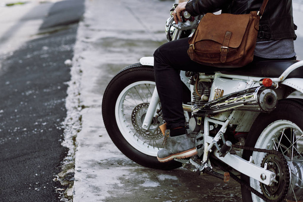 Teilansicht eines Motorradfahrers, der auf einem Oldtimer-Motorrad sitzt und Gas gibt - Foto, Bild
