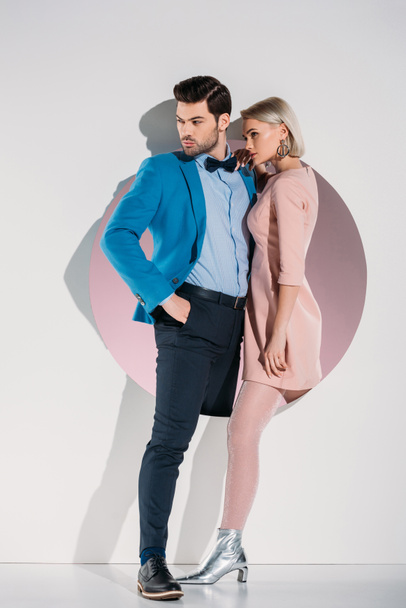 beautiful fashionable couple in love looking away while standing together in hole on grey - Foto, Bild