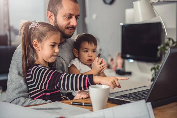 Father with daughter and son on his lap watching laptop - Photo, Image