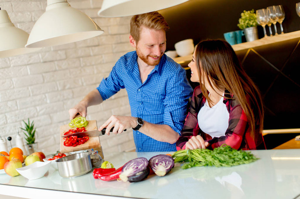 Preciosa pareja joven preparando comida saludable en la cocina moderna
 - Foto, Imagen
