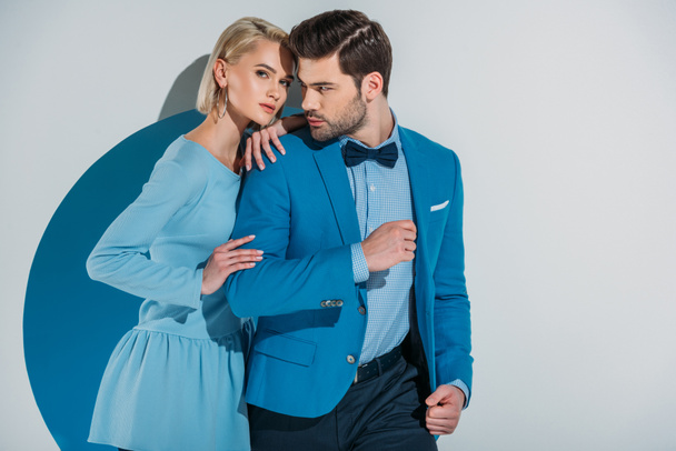 mooi paar stijlvolle blauw pak en jurk staande samen in diafragma op grijs - Foto, afbeelding