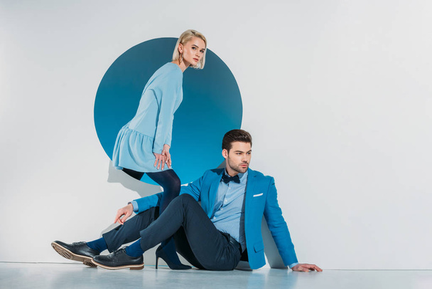 beautiful stylish young couple posing near blue hole on grey - Фото, зображення