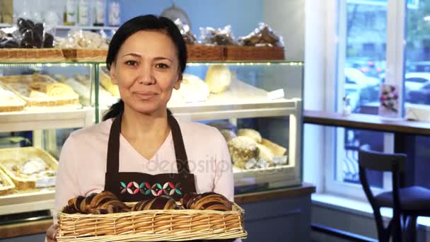 Dorosła kobieta baker pozowanie w jej sklepie z kosz pełen rogaliki - Materiał filmowy, wideo