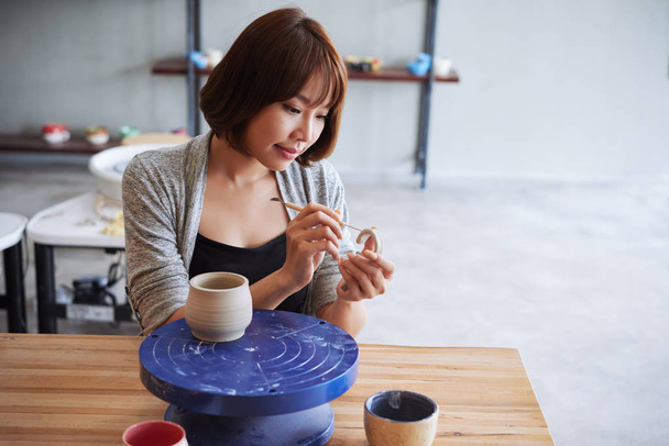 Asiatico giovane donna intaglio maniglia per il suo argilla tazza
 - Foto, immagini