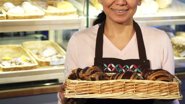 Foto recortada de una pastelera alegre posando con una cesta llena de croissants
 - Metraje, vídeo
