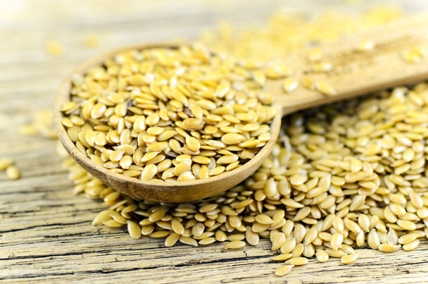 Spoonful of golden flax seed on wood background. - Photo, Image