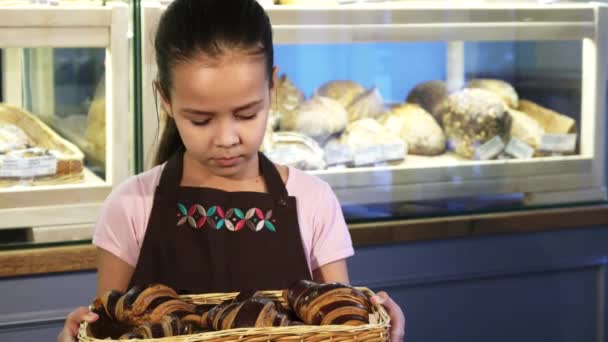Aranyos kis lány visel kötény dolgozik a pékség, mosolyog a kamerába - Felvétel, videó