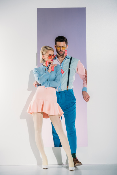 fashionable young couple with sale labels on clothes standing in opening on grey  - Foto, Imagem