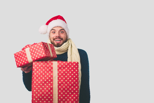 Handsome man in a Christmas hat holding gifts on white background - Foto, imagen