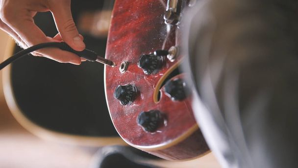 Musician plugs in and tunes his guitar before a performance, hands close up - Photo, Image