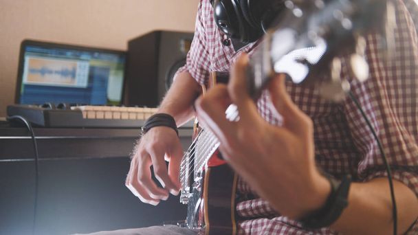 Νεαρός μουσικός συνθέτει και ηχογραφεί μουσική να παίζει ηλεκτρική κιθάρα χρησιμοποιούν υπολογιστή και πληκτρολόγιο - Φωτογραφία, εικόνα