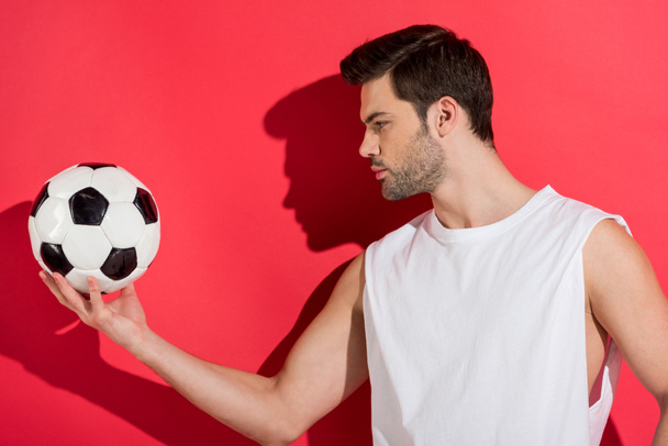 handsome young man holding soccer ball on pink - Fotó, kép