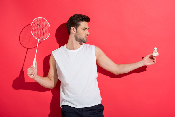 handsome young man holding badminton racket and shuttlecock on pink - Photo, Image