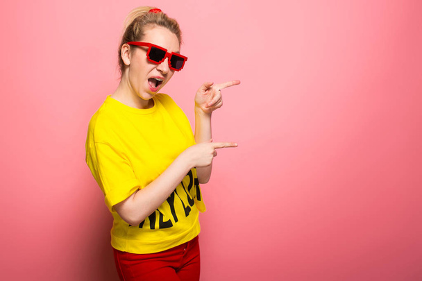 Expressieve jongedame helder geel t-shirt en zonnebril dragen op roze achtergrond - Foto, afbeelding