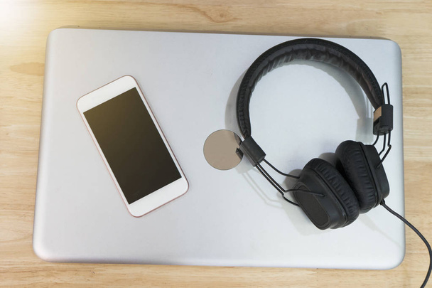 Słuchawki i inteligentny telefon jest umieszczony na laptopie. Koncepcja relaks - Zdjęcie, obraz