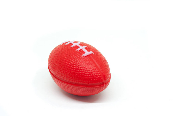 Nahaufnahme rotes Rugby-Ball-Spielzeug für Kinder isoliert auf weißem Hintergrund. (Selektiver Fokus) - Foto, Bild