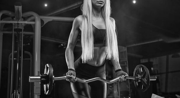 Young beautiful girl athlete bodybuilder at the gym doing exerci - Fotó, kép
