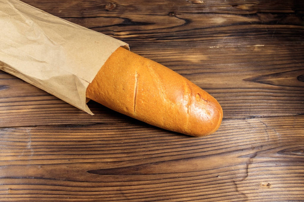 Baguete francesa em saco de papel na mesa de madeira
 - Foto, Imagem
