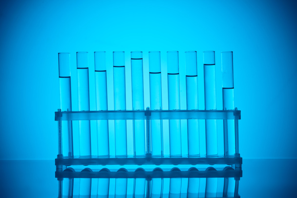 fila de tubos de vidrio con líquido en pie sobre azul
 - Foto, Imagen
