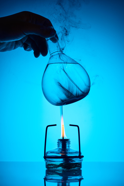 immagine ritagliata del chimico che riscalda la sostanza per l'analisi sul blu
 - Foto, immagini