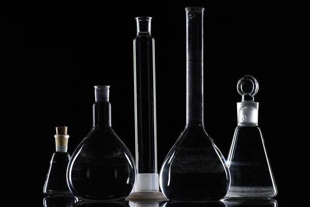 transparant glas kolven met stof in laboratorium op zwart - Foto, afbeelding