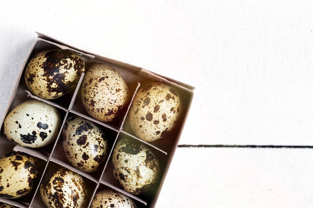 Easter spring composition, box with quail eggs. Close up portrait on white wooden background with place for text. - Fotografie, Obrázek