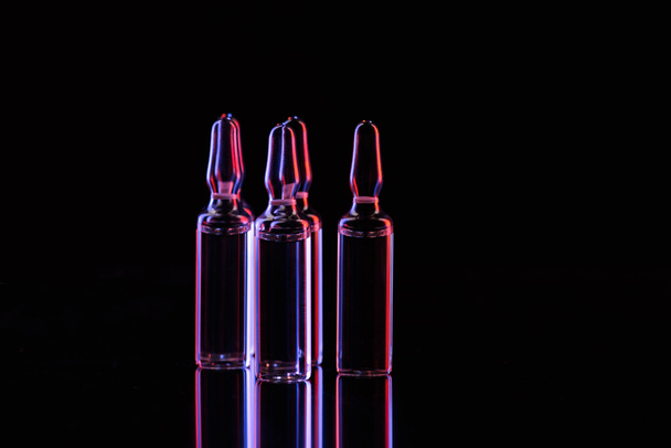 transparent glass ampoules with liquid on table on black - Fotó, kép