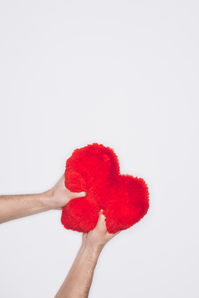 cropped shot of angry man squeezing soft red heart pillow isolated on white - Photo, Image