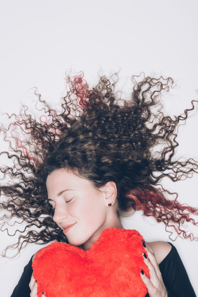 красивая молодая женщина с подушкой в форме сердца изолированы на белом
 - Фото, изображение