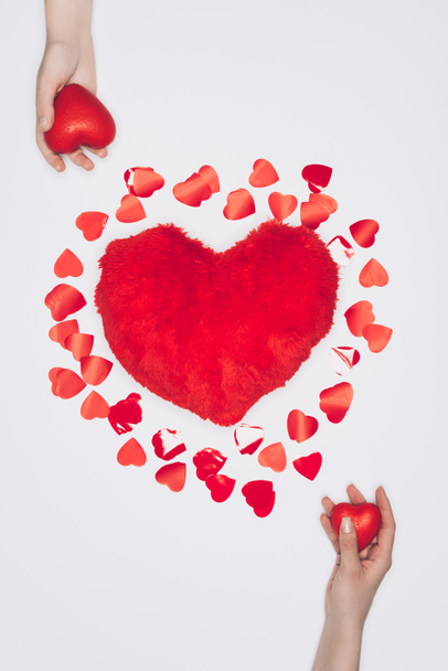 Minik kalpler üzerinde beyaz eller ile izole ile çevrili kalp şeklinde tüylü yastık Üstten Görünüm - Fotoğraf, Görsel