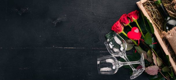 A bottle of red wine and a bouquet of red roses. Valentines day. On a wooden background. Top view. Free space for your text. - Photo, image
