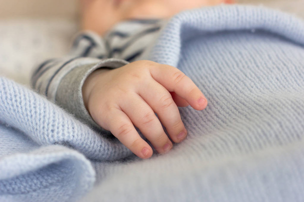 Hand van een baby met kleine vingers op een blauwe deken - Foto, afbeelding