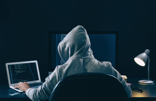 Man wearing hoodie hacking server in dark room - Photo, image
