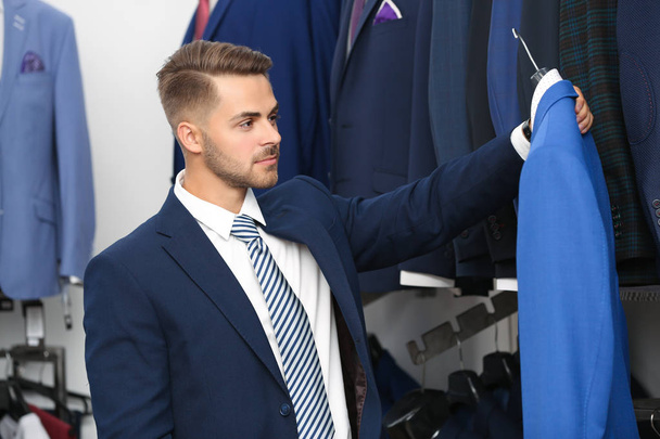 Young man choosing suit in store - Foto, imagen