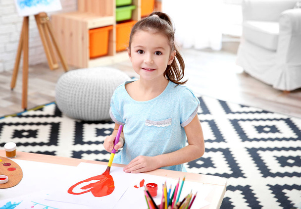 Little girl painting at table indoors - Fotó, kép