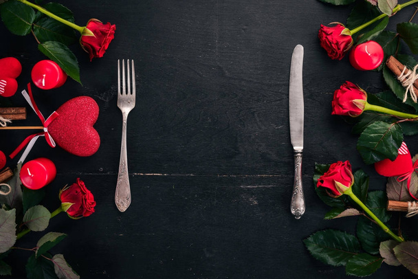 Serving the table to celebrate Valentine's day. Cutlery, plate, roses. On a wooden background. Top view. Free space for your text. - Fotografie, Obrázek