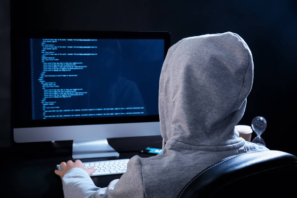Man wearing hoodie hacking server in dark room - Fotó, kép