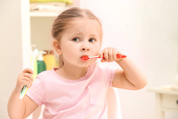 Cute little girl brushing teeth in bathroom - Foto, imagen