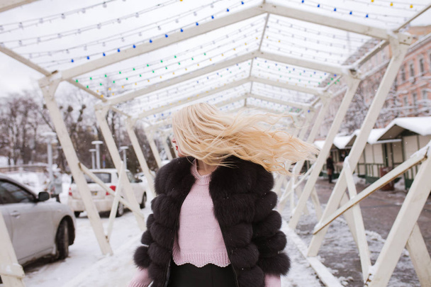 Elegante joven en abrigo de piel caliente posando con el pelo en movimiento
  - Foto, imagen