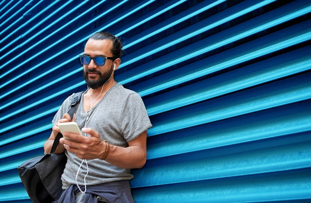 man with earphones and smartphone over wall - Foto, imagen