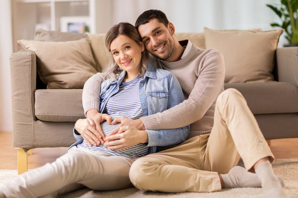 man with pregnant woman making hand heart at home - Foto, Bild