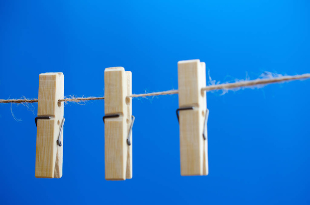 Mavi bir arka plan üzerinde bir ip üzerinde bir kaç clothespins dönüştürün - Fotoğraf, Görsel