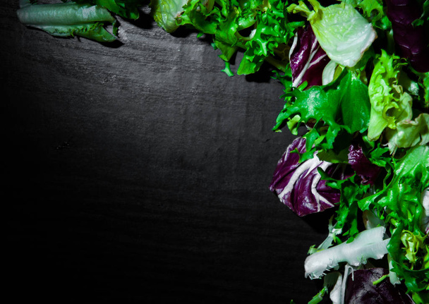 various fresh salad leaves with lettuce, radicchio, and rocket on dark wooden background with copy space. top view - Valokuva, kuva