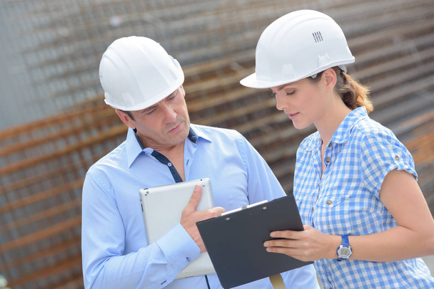 Man and woman in hardhats looking at clipboard - Foto, Bild