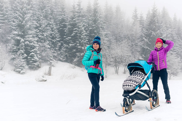 Mutter mit Kinderwagen genießt Mutterschaft im Winterwald - Foto, Bild